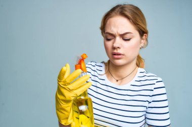 Elinde bir kova temizlik malzemesiyle eve bakan bir kadın.