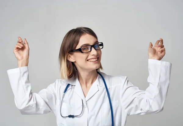 Enfermera con un vestido médico haciendo gestos con las manos sobre un fondo claro —  Fotos de Stock