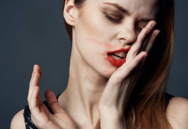 Parlak makyajlı ve yüzünde ruj lekesi olan bir kadın.