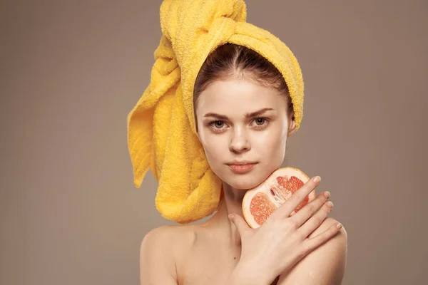 Kvinna med bara axlar gul handduk på huvudet grapefrukt i händerna ren hudvård — Stockfoto