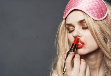 Sarışın, ruj lekeli. Yüzünde makyaj ve göz farı var.