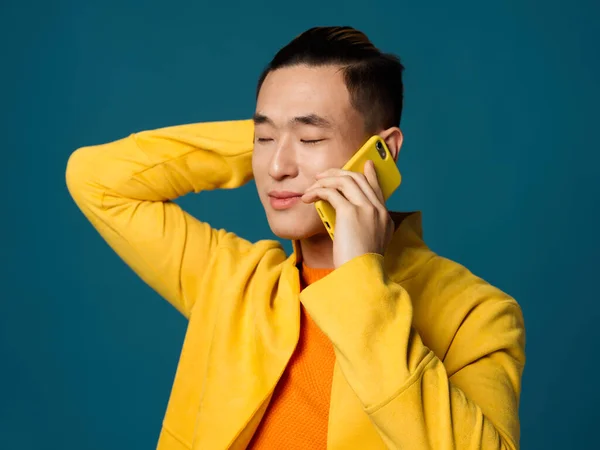 青い背景に電話で話してる黄色いジャケットのビジネスマン — ストック写真