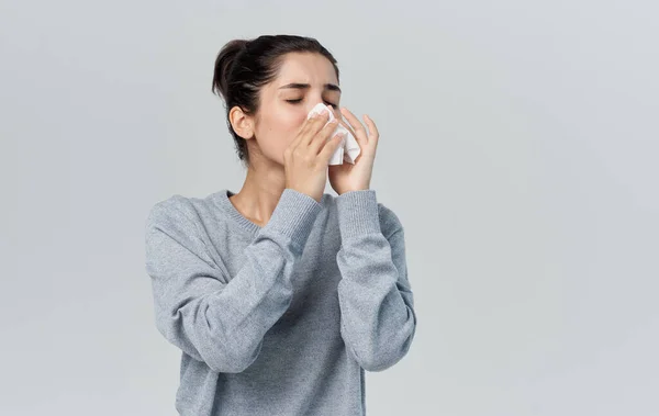 Άρρωστη γυναίκα φυσάει τη μύτη της με χαρτοπετσέτα σε γκρι φόντο και ζεστό πουλόβερ περικοπή άποψη — Φωτογραφία Αρχείου