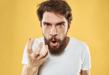 Öfkeli bakışları olan sarı arka planda öfkeli bir adam elleriyle işaret ediyor.