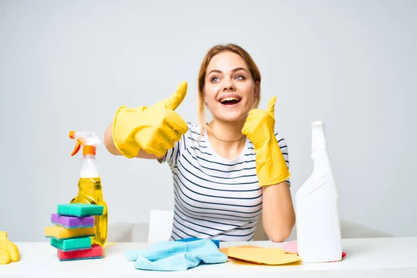 Masada oturan kadın lastik eldivenler ev işi deterjan servisi temizliyor. — Stok fotoğraf