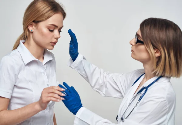 Medico donna in abito medico e guanti blu con uno stetoscopio intorno al collo e una paziente donna — Foto Stock
