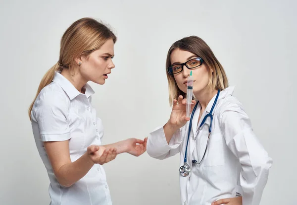 Медсестра в медичній сукні тримає шприц в руці і пацієнт на легкому тлі — стокове фото