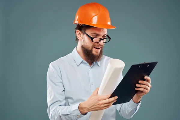 Man in orange hard hat blueprints in hands construction industry blue background — Stock Photo, Image