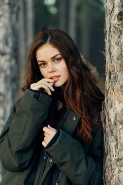 Sonbahar ceketli bir kadın ağaçların orada dinleniyor.