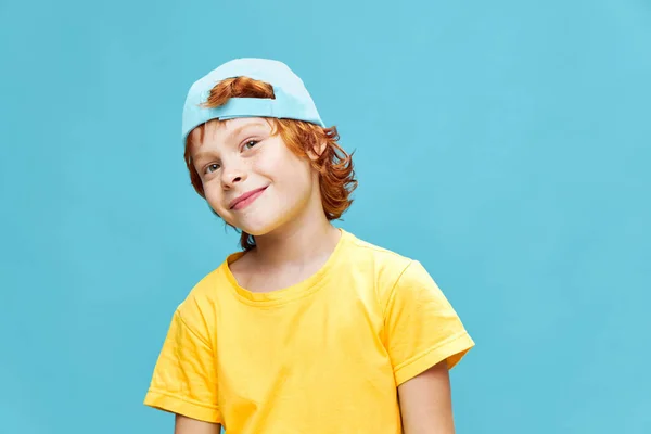 Ένα κοκκινομάλλικο αγόρι με ένα καπέλο στο κεφάλι του έγειρε το κεφάλι του στο πλάι. — Φωτογραφία Αρχείου