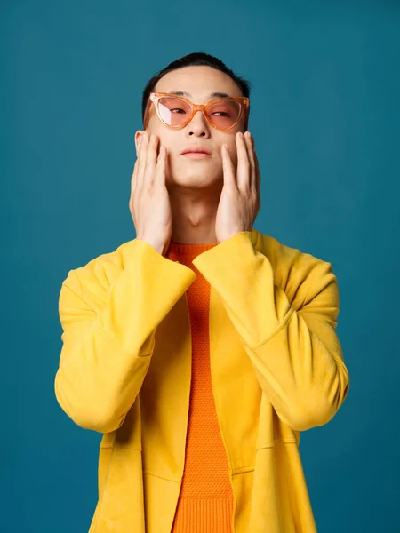 Un uomo con gli occhiali inclinato la testa indietro giacca gialla sfondo blu — Foto Stock