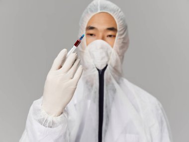 Erkek laboratuvar asistanı bir test aşısının elindeki şırıngayı inceliyor.
