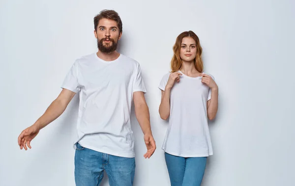 Ein Mann und eine schöne Frau in derselben Kleidung auf hellem Hintergrund gestikulieren mit ihren Händen — Stockfoto
