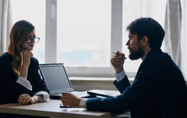 Takım elbiseli bir iş adamı ve bir kadın iş yerinde ofiste karşılıklı iletişim kuruyor.