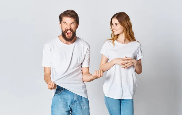 Συναισθηματική άνθρωπος σε ένα t-shirt και μια γυναίκα σε τζιν σε ένα ελαφρύ φόντο ύφασμα ρούχα μόδας στυλ — Φωτογραφία Αρχείου