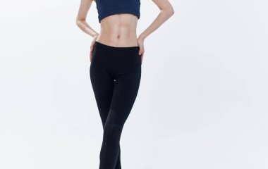 Kısa tişörtlü ve siyah taytlı bir kadın elini belinden açık arka planda tutuyor.