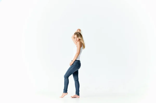 Donna in jeans e t-shirt bianca su fondo chiaro in piena crescita — Foto Stock