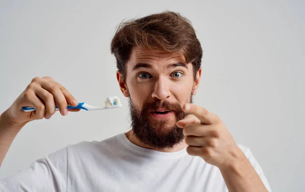 Hombre con un cepillo de dientes en sus manos modelo de pasta dental para el cuidado de la cavidad oral — Foto de Stock