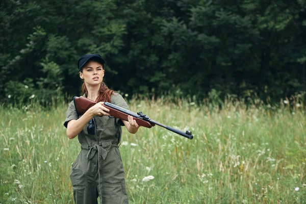 Woman on nature gun in hand fresh air traveler hunting green overalls — Stock Photo, Image