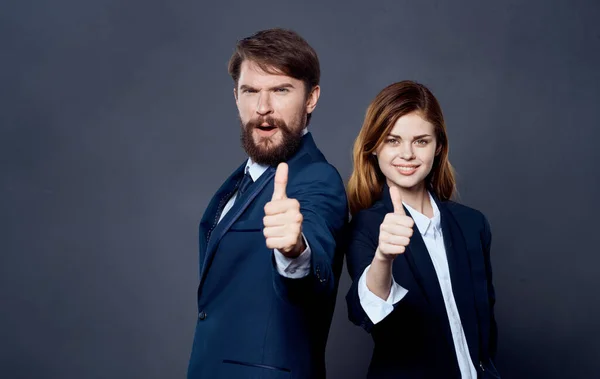 Business successful people in suits stand with their backs to each other on a gray background confident look