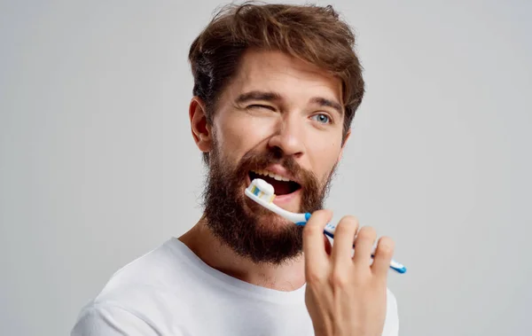 Hombre con un cepillo de dientes en sus manos modelo de pasta dental para el cuidado de la cavidad oral — Foto de Stock