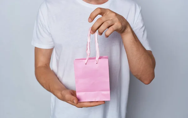 Modelo homem com saco de presente na mão em feriados fundo luz — Fotografia de Stock