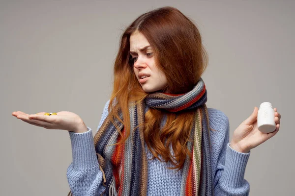 Vrouw met een pot pillen op een grijze achtergrond en een sjaal ziekte virale infectie — Stockfoto