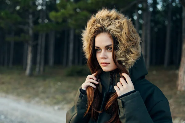 フード付きの暖かいジャケットを着た女性は、森の中で自然に目を向ける髪を持っています。 — ストック写真