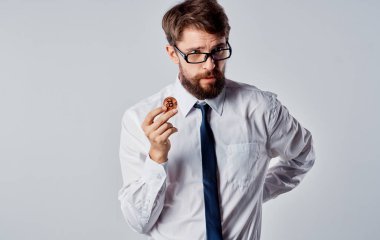 Elinde altın sikke olan, arka planda hafif bir adam Bitcoin kripto para işinin şaşkın bakışlarını sergiliyor.