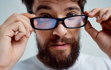 Gözlüklü beyaz tişörtlü sakallı adam.