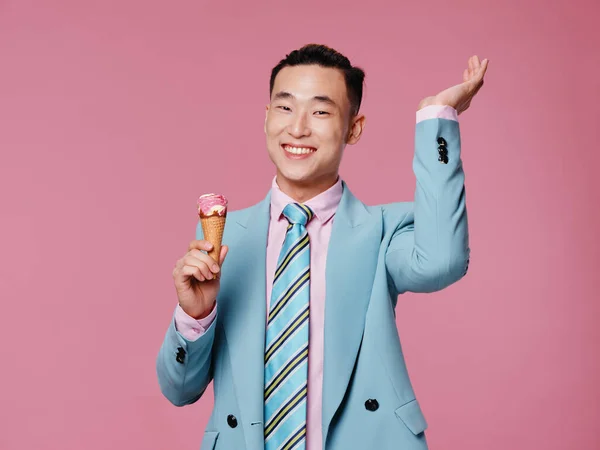 Hombre de asiático apariencia en azul traje helado en manos emociones rosa fondo —  Fotos de Stock