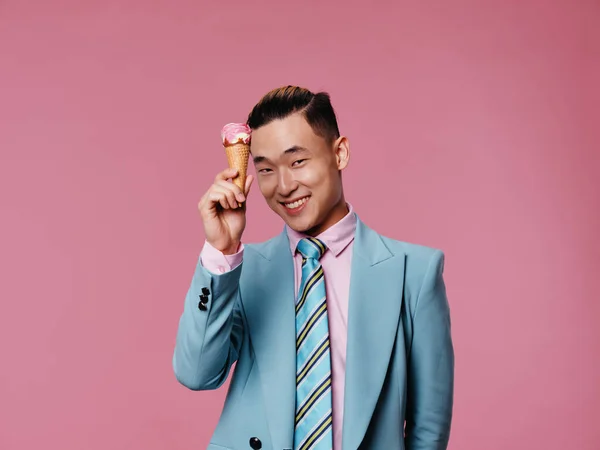 Hombre alegre en un traje azul helado en las manos de la alegría fondo rosa —  Fotos de Stock