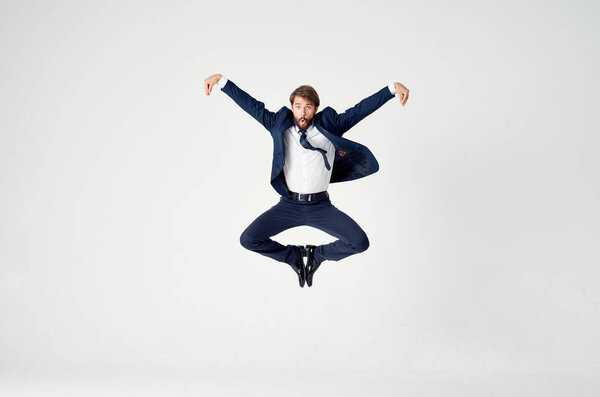 Энергичный бизнесмен в синем костюме прыгает на легком фоне успеха