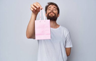 Arka planda hafif tatillerde elinde hediye çantası olan model adam.