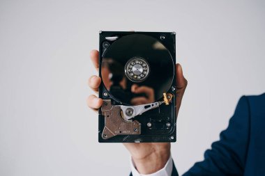 Hard disk, gri bir arka planda bir adamın elinde parçalara ayrıldı.