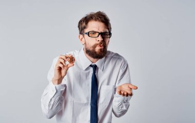 Elinde bozuk para olan bir adam arka planda bitcoin kripto para görüntüsünü kırpmış.