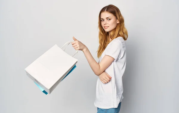 Красивая женщина в белой футболке с пакетами в руках покупки изолированный фон — стоковое фото