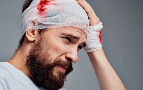 Ένας άντρας με μια επίδεσμη στο κεφάλι χειρουργική επέμβαση ανάνηψης του αίματος μοντέλο γάζα στο χέρι του — Φωτογραφία Αρχείου