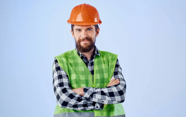 Um trabalhador da construção civil em um capacete gestos com as mãos e um colete reflexivo — Fotografia de Stock