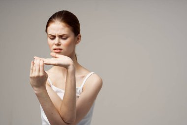 Elleri hafif arka planda, beyaz tişörtlü bir kadın el kol hareketi yapıyordu.