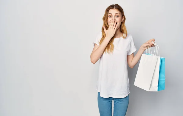 Linda mujer pelirroja en una camiseta blanca con paquetes en las manos comprando fondo aislado. — Foto de Stock