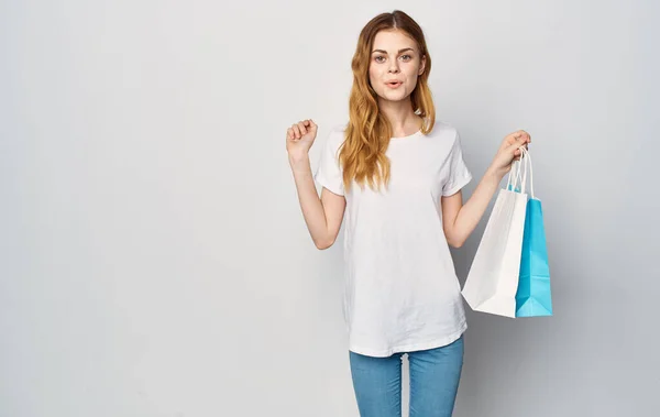 Mujer en camiseta blanca y paquete de jeans en manos estudio recortado ver fondo aislado Shopaholic — Foto de Stock