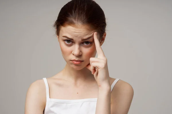 Mujer joven tocándose la cara con las manos en un fondo gris problemas de salud cosmetología cuidado del acné —  Fotos de Stock