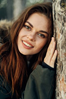 Güzel bir kadın ağaca sarılıyor. Yakından bak.