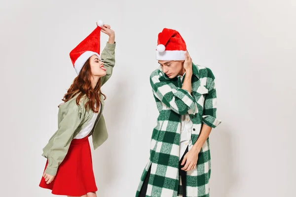 Uma mulher bonita e um jovem em um chapéu festivo estão se divertindo em um fundo leve — Fotografia de Stock