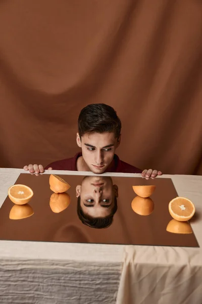 Hombre en la mesa con naranjas y fondo de tela — Foto de Stock