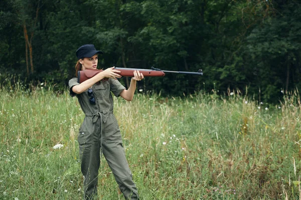 Woman on nature Green overalls with a gun in front of him fresh air — Stock Photo, Image