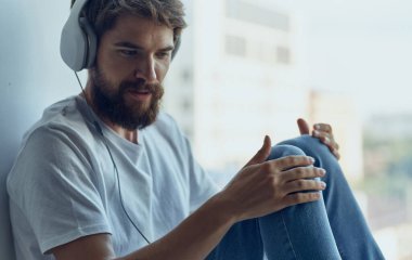 Kulaklıklı genç pencere kenarında oturur. İç modelini gevşetir.