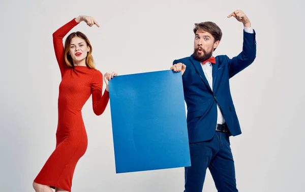 Γυναίκα με κόκκινο φόρεμα κομψός άντρας σε κοστούμι με μπλε φύλλο χαρτιού στα χέρια του διαφημιστικού πρακτορείου — Φωτογραφία Αρχείου