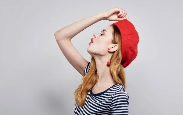 Femme en t-shirt rayé touche chapeau rouge sur son fond clair de la tête vue recadrée — Photo